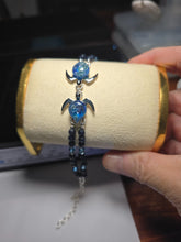 Real Akoni Silver double sea turtle bracelet with blue glass shells, dark blue beads and light-blue accent beads on a cream display.
