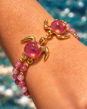 Kuipo double sea turtle bracelet with pink glass shells and pink beads, shown in Gold on a wrist.